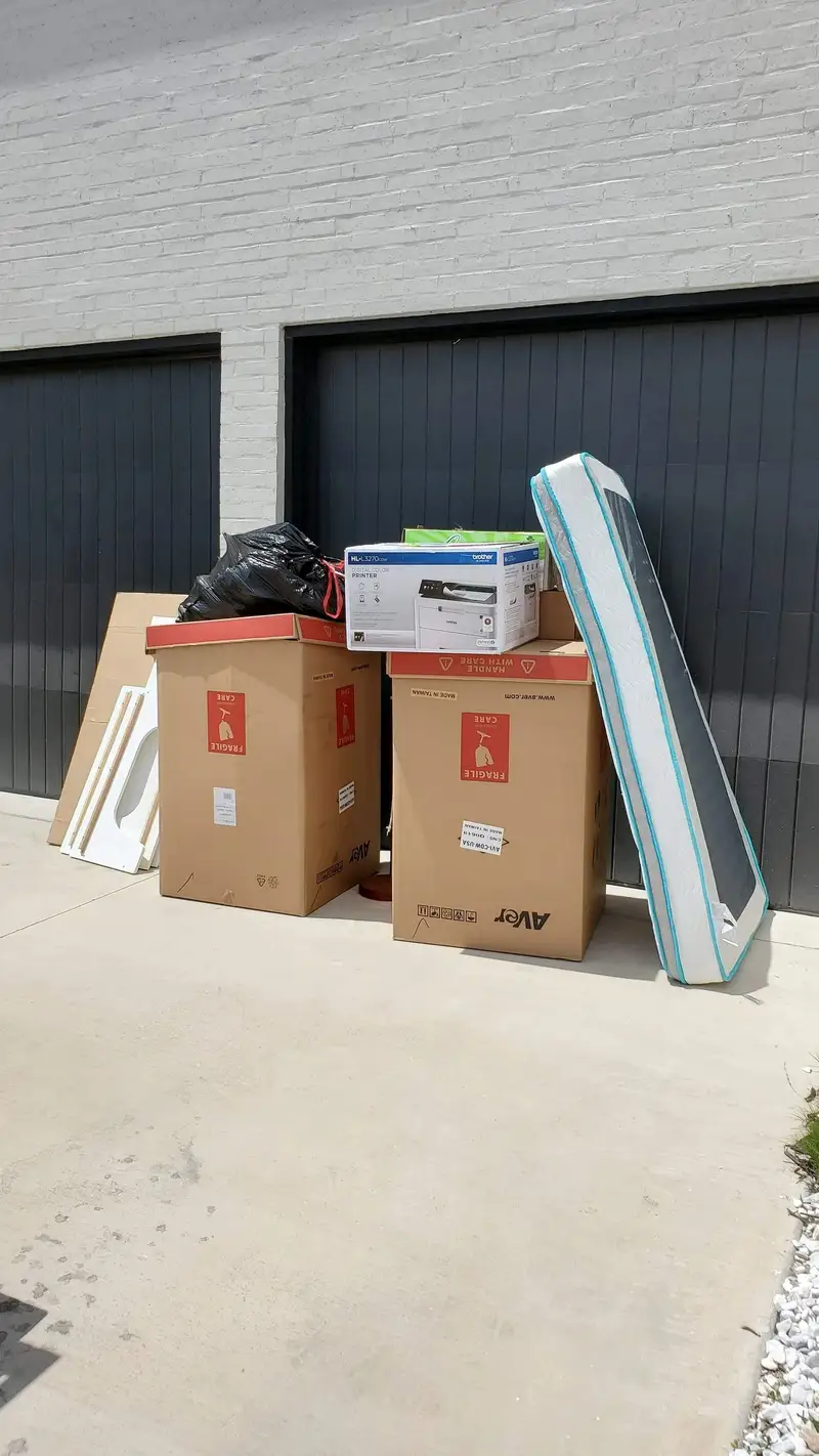 Mattress and boxes staged outside a garage for pickup